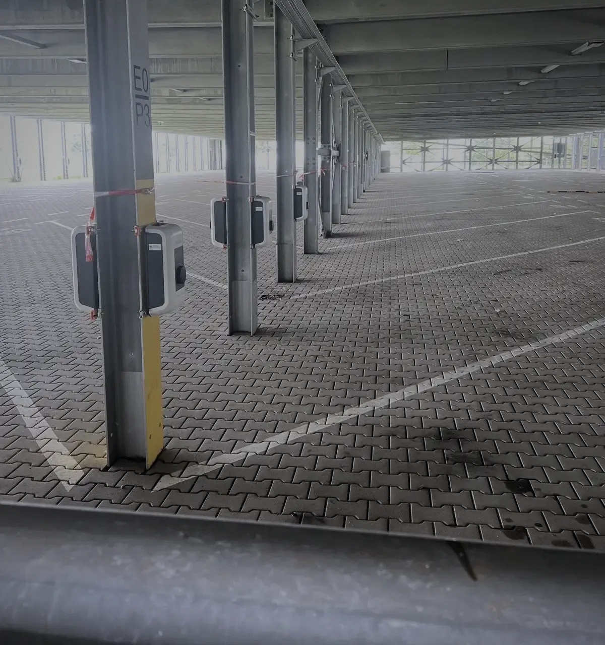 Lange Reihe von Wallboxen an den Stützen eines Parkdecks, Stellplatz für Stellplatz