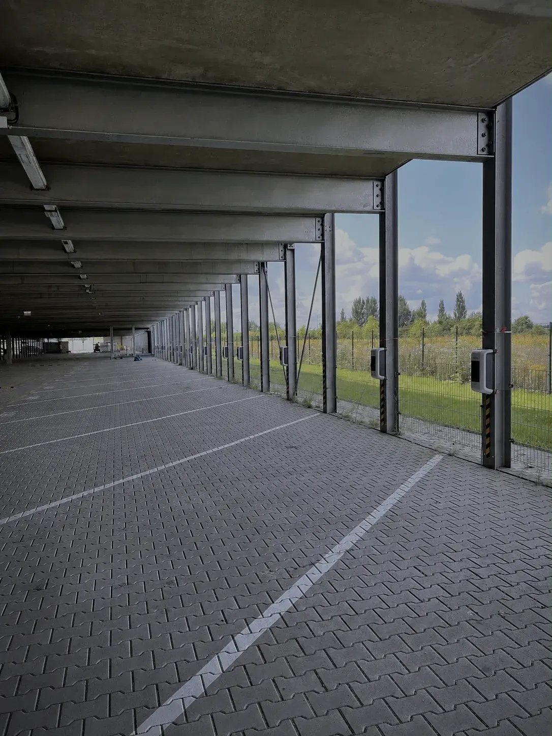 Parkdeck-Ebene mit Stützenreihe und Ladepunkten über die gesamte Länge